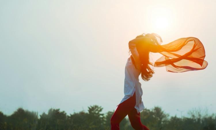 A woman with a flowing orange scarf in a sunlit field, representing the different types of FIRE